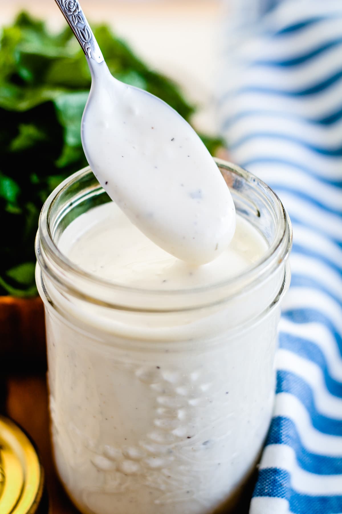 A spoon being dipped into a jar of homemade ranch dressing.