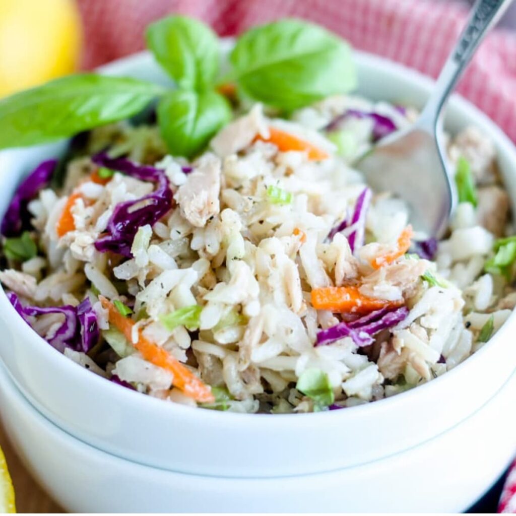 A bowl of rice salad with tuna with a fork in it.