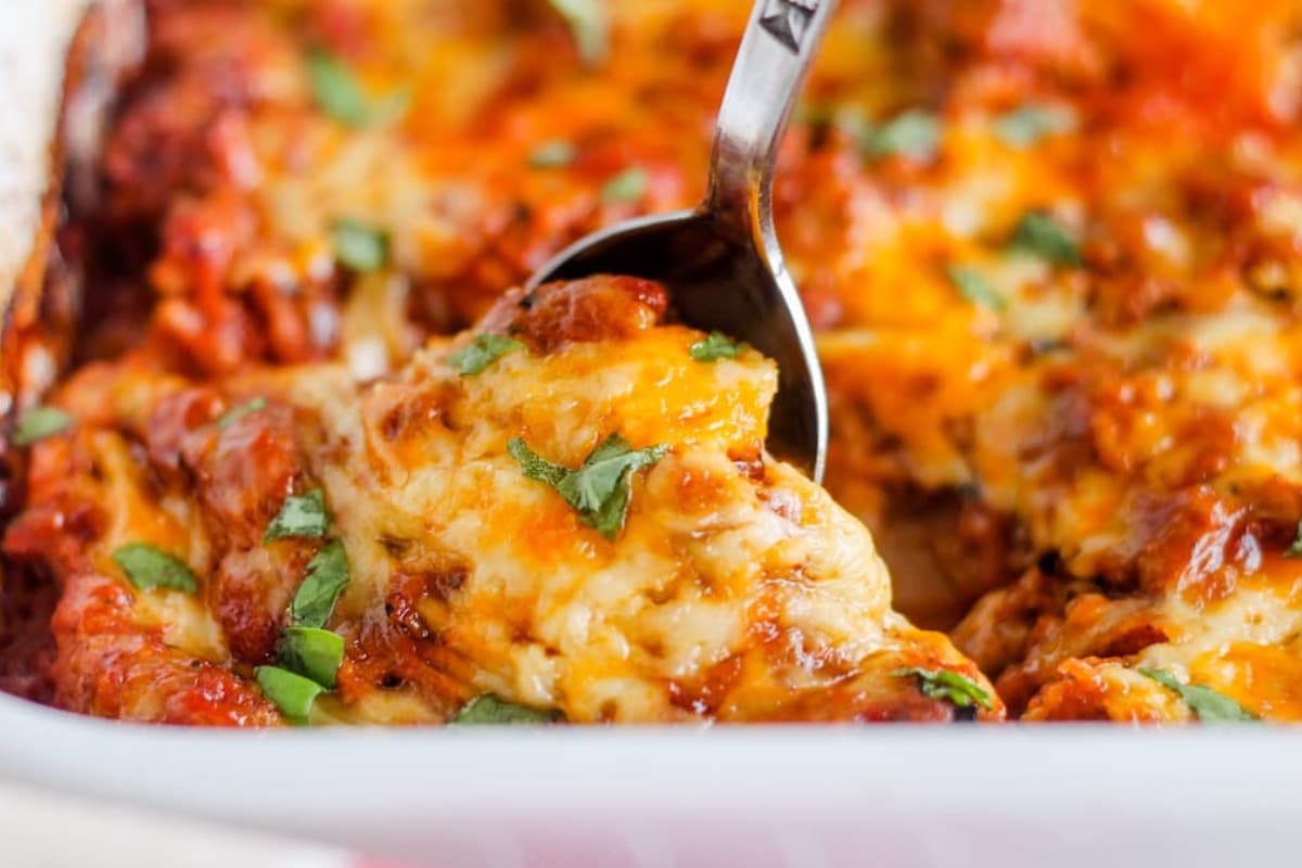 A spoon scooping ground beef casserole from a dish.