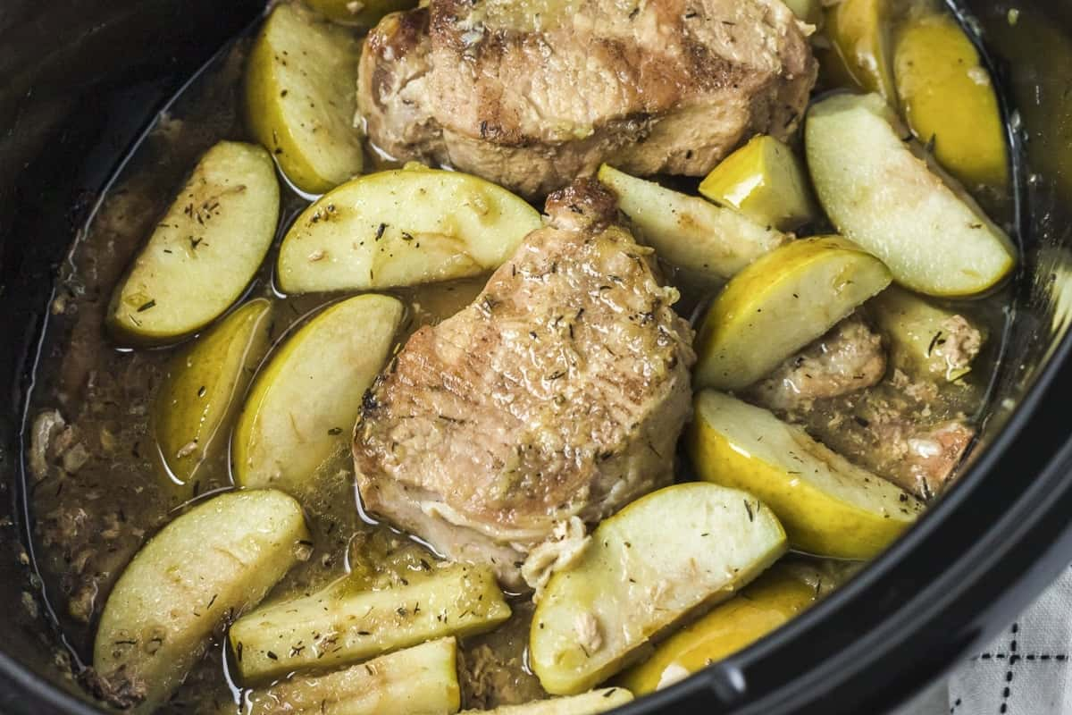 A pot of slow cooker pork chops and apples.