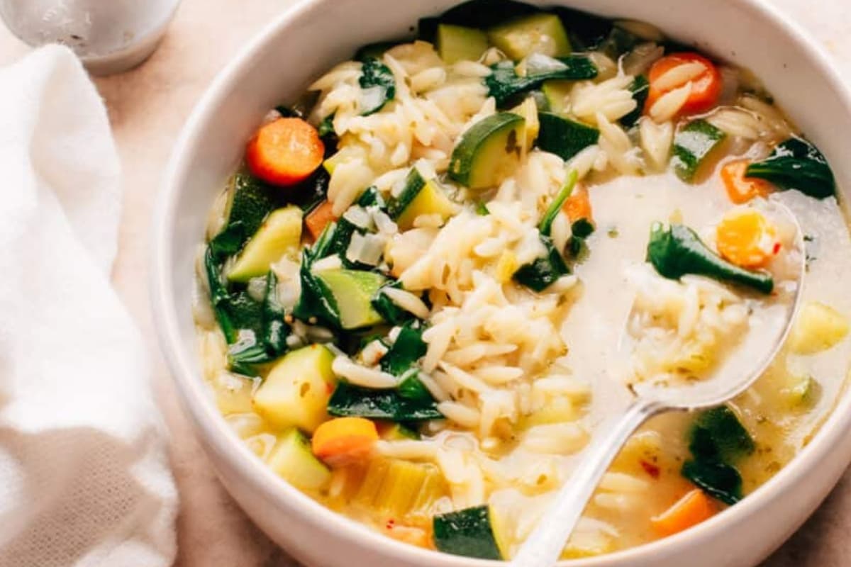 A bowl of vegetable orzo soup.