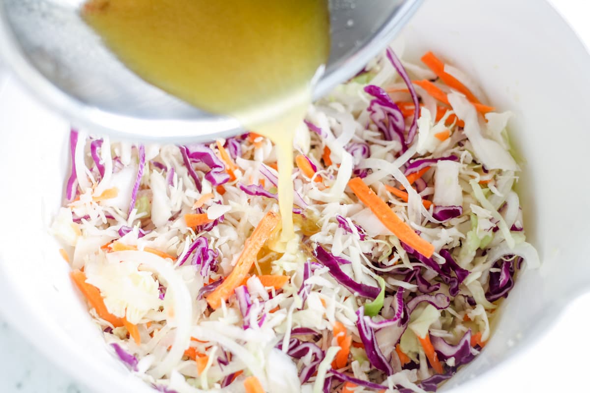 Dressing being poured over ingredients in a bowl.