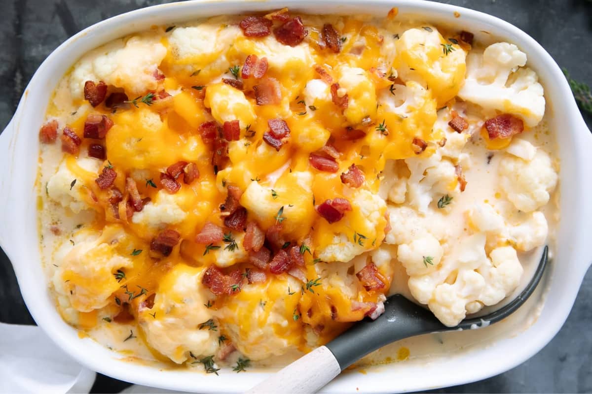 A dish of cheesy cauliflower with bacon.