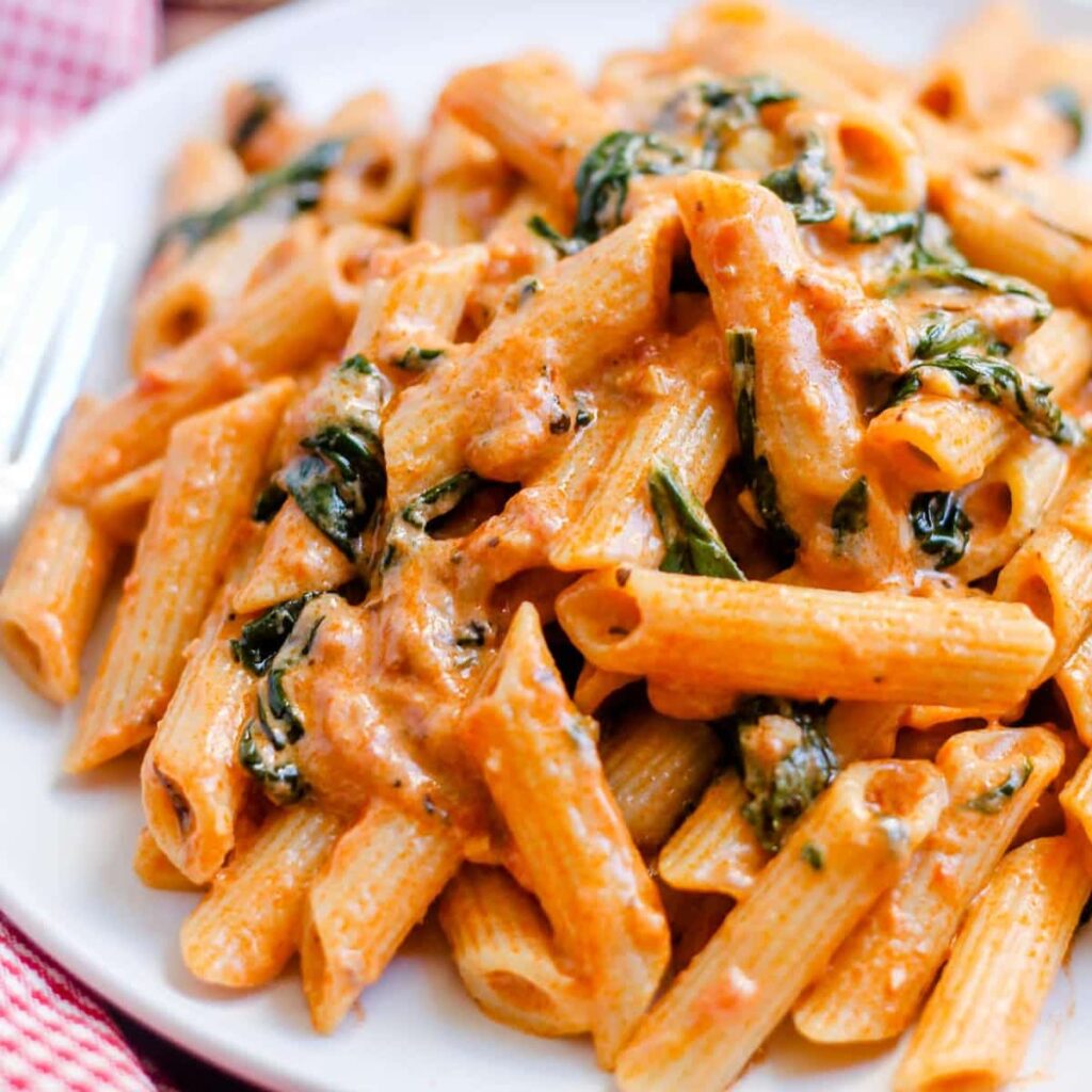 A plate of creamy tomato spinach pasta.