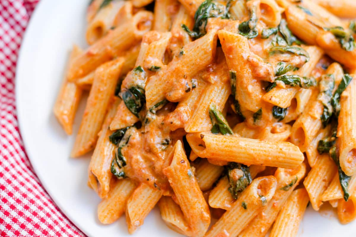 A plate of creamy tomato spinach pasta.