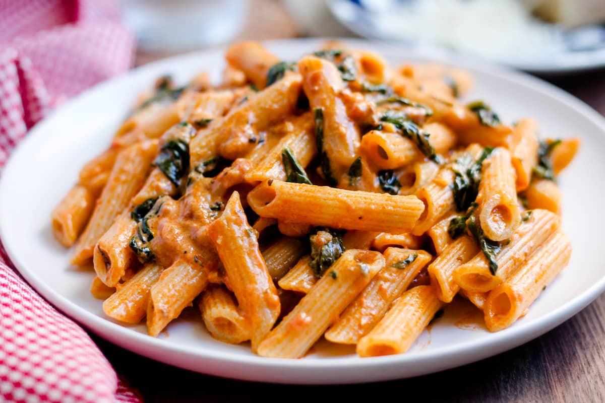 A plate of creamy tomato spinach pasta.