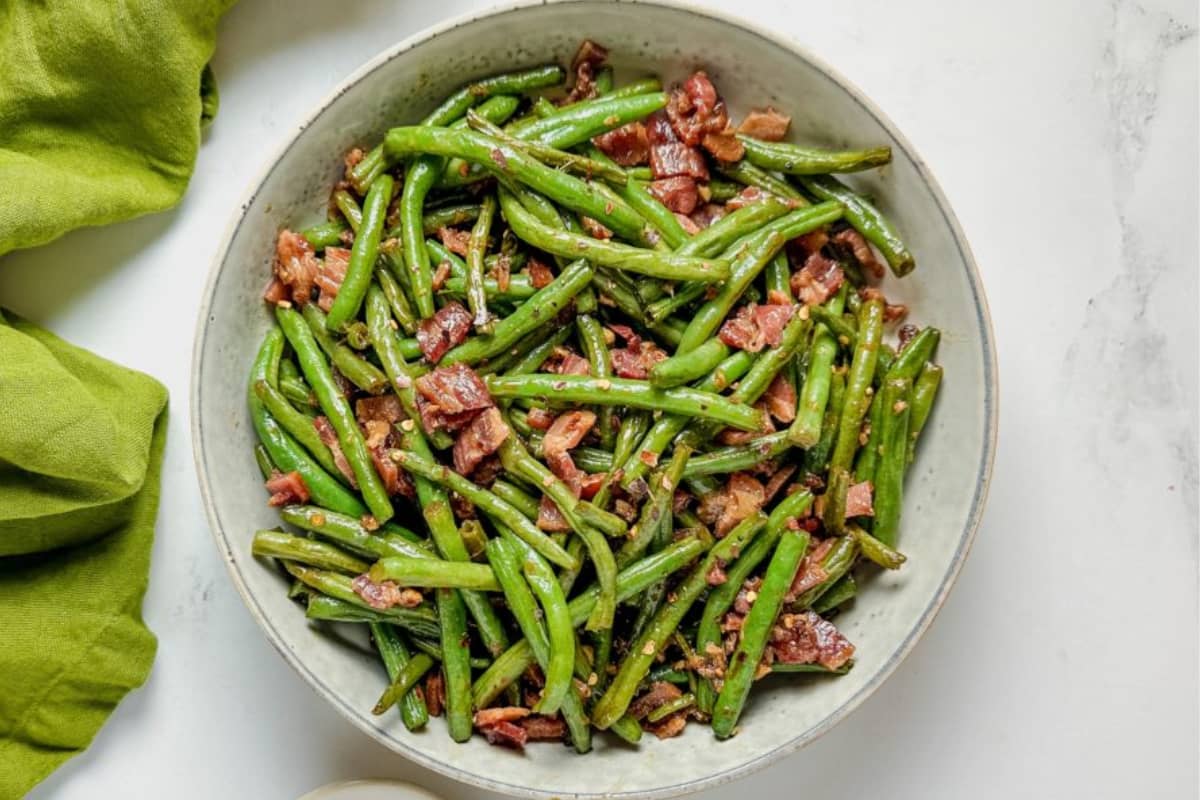 A bowl of green beans with bacon.