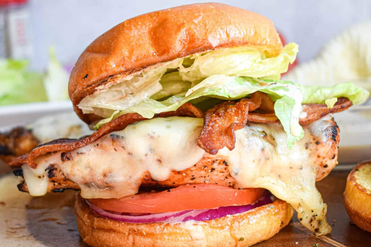 A grilled chicken sandwich on a board.