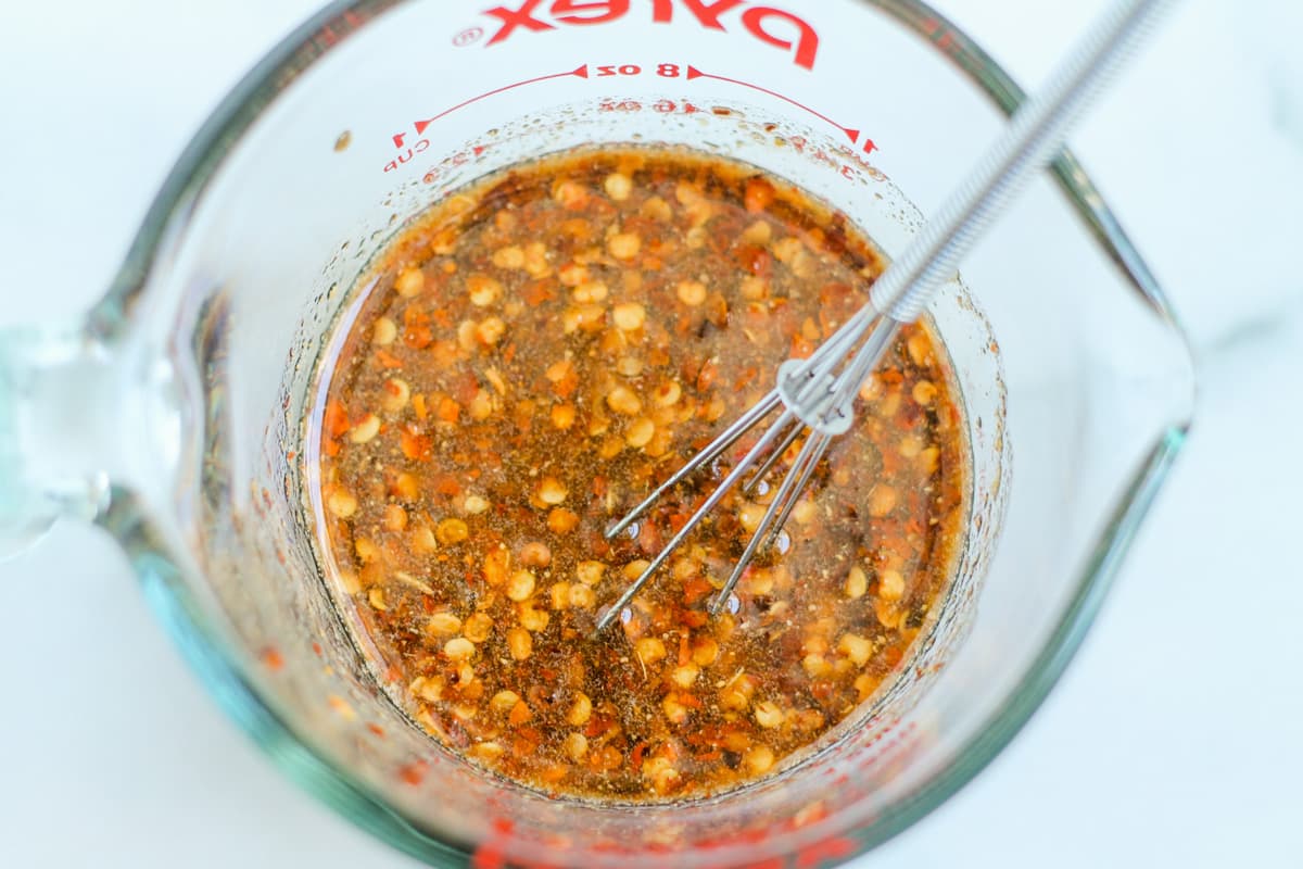 Sauce being stirred in a glass measuring cup.