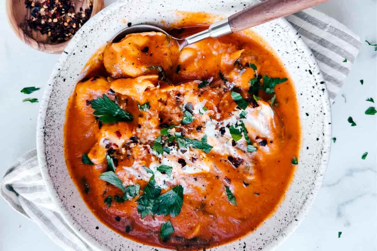 A bowl of tomato tortellini soup.