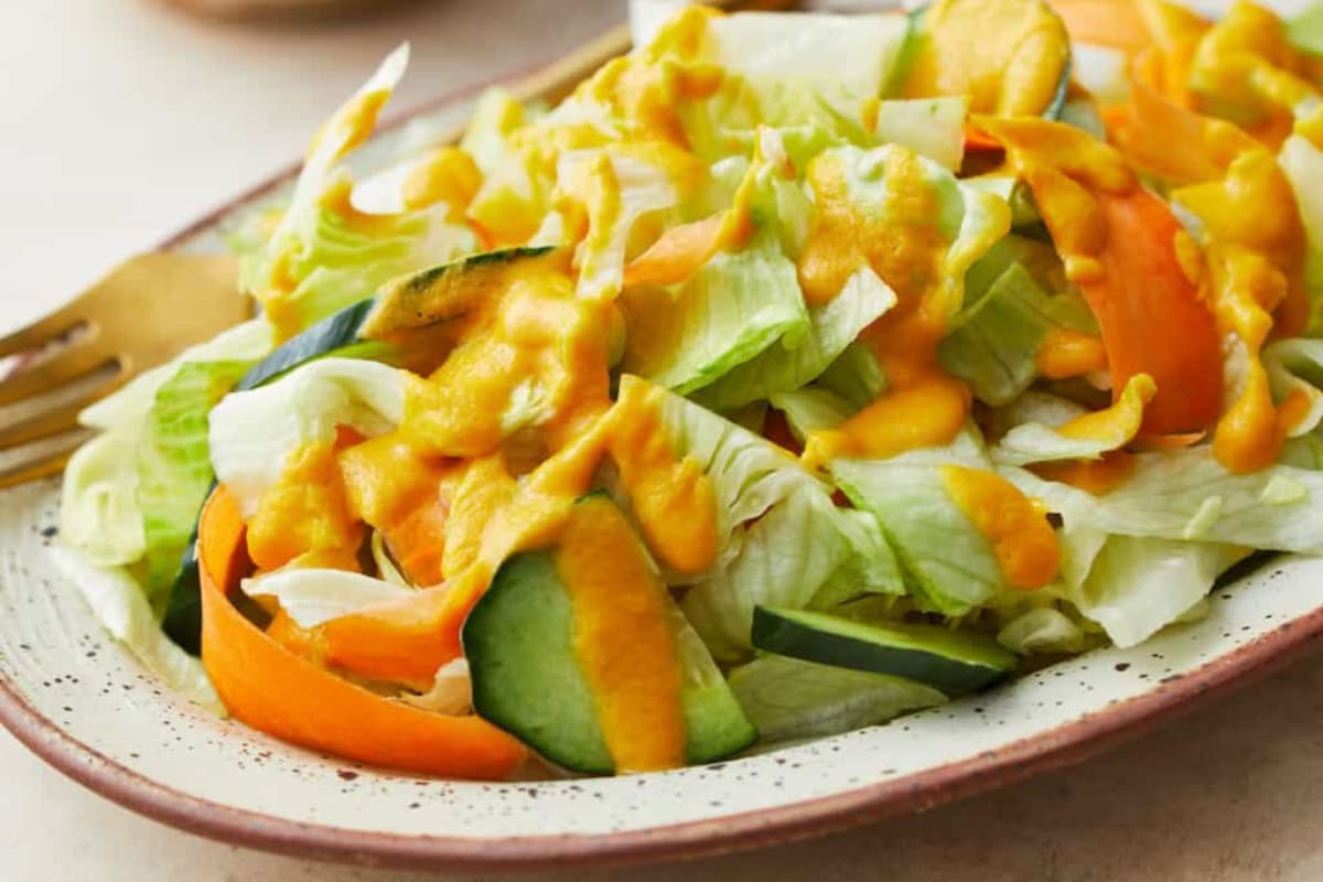 A plate of salad with ginger salad dressing.