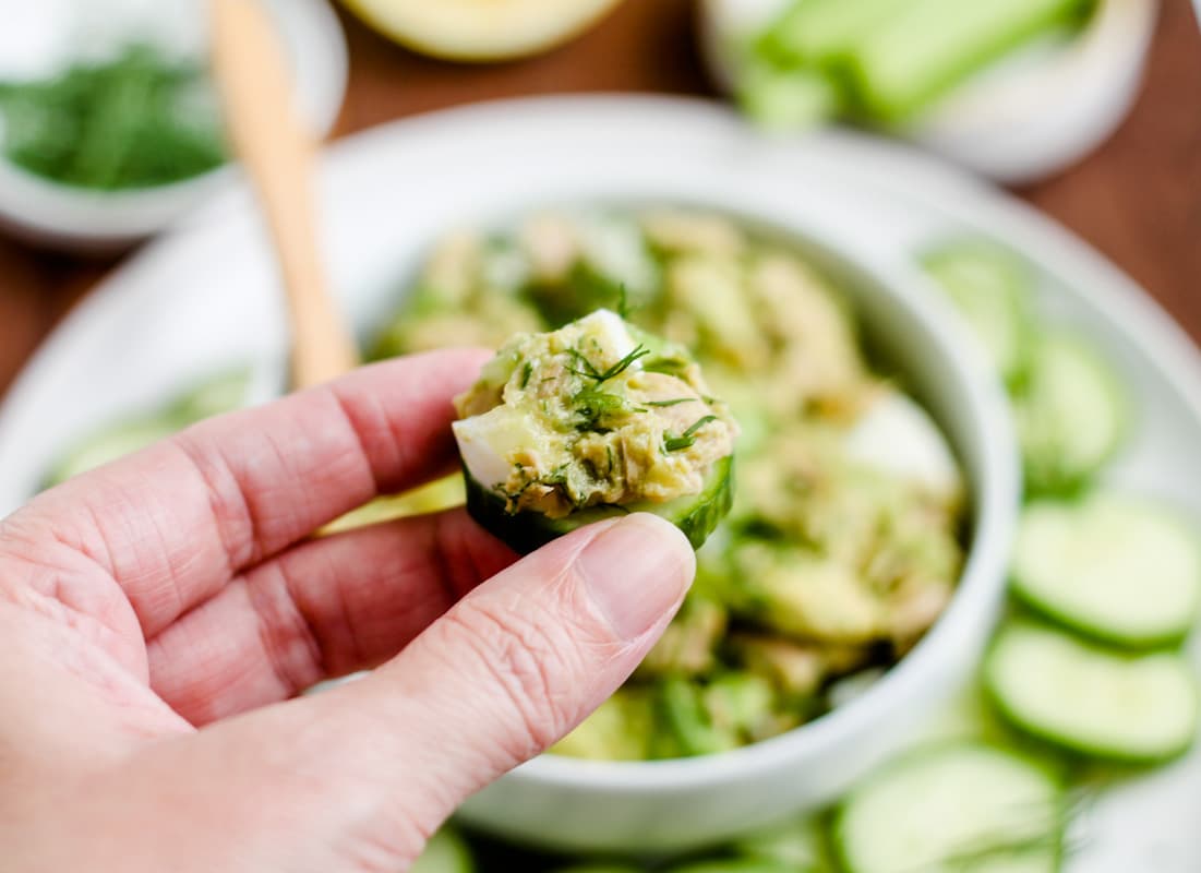 A hand holding a cucumber slice.