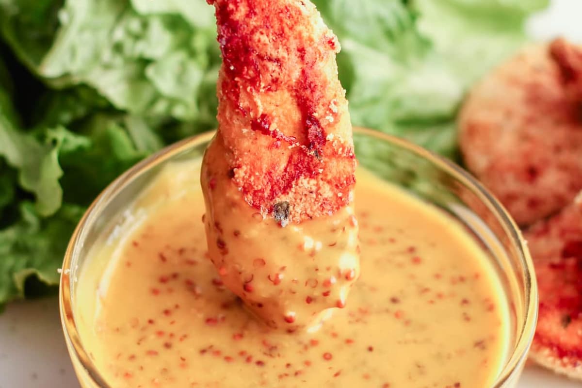 A gluten free chicken tenders being dipped into sauce.