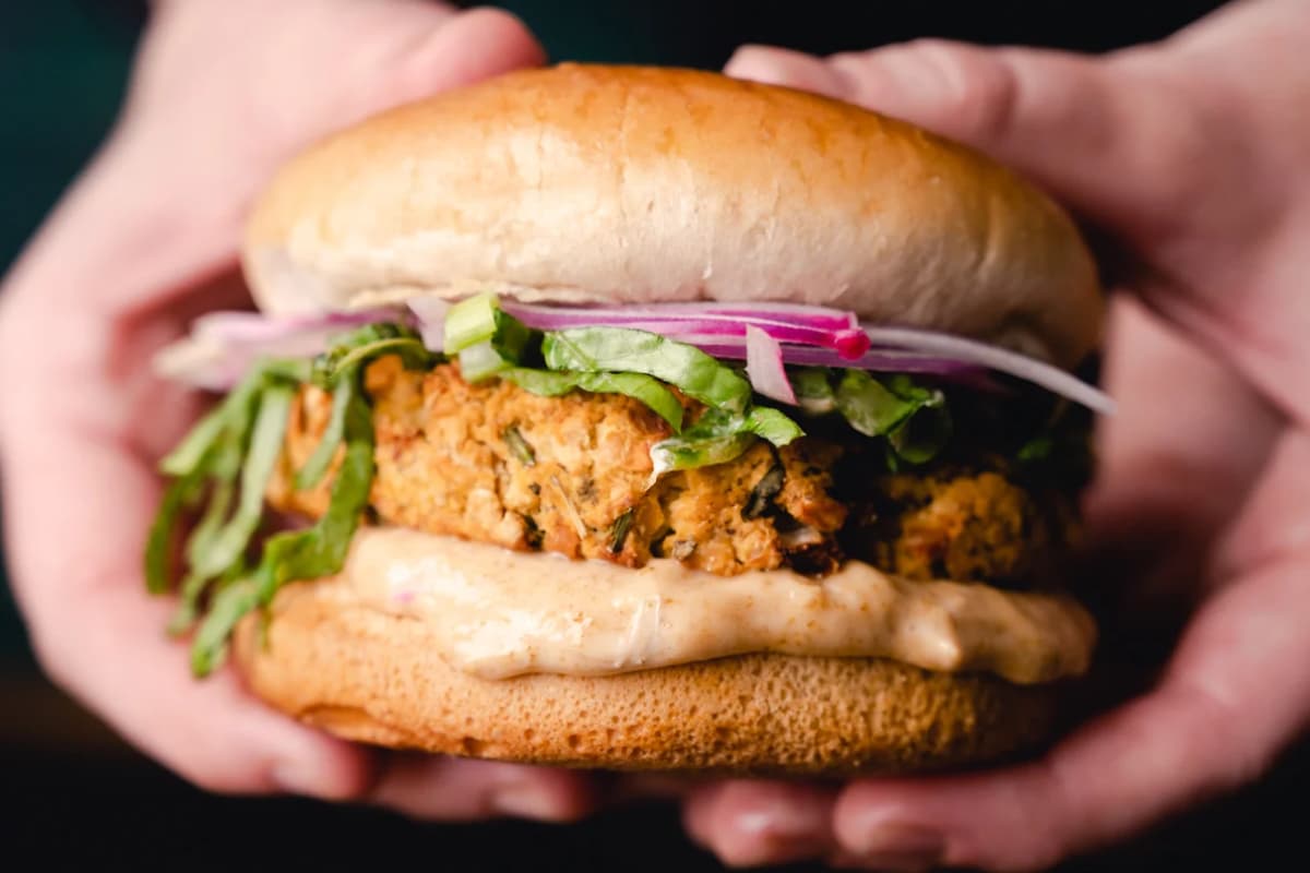 A hand holding a chickpea burger.