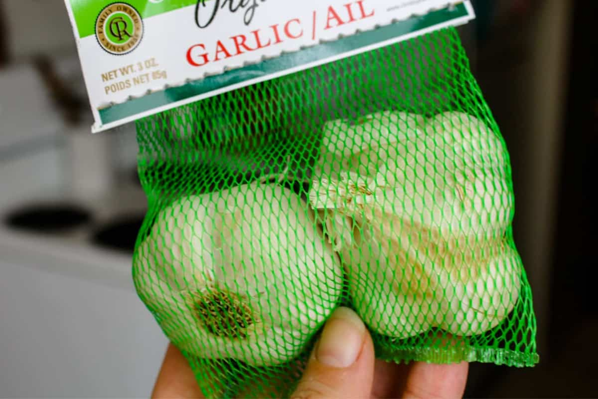 A hand holding a bag of garlic.