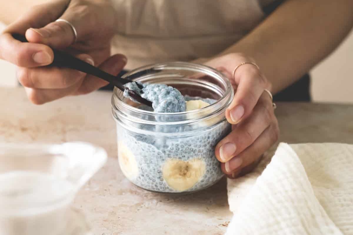 A hand scooping a spoonful of high protein blue chia pudding.