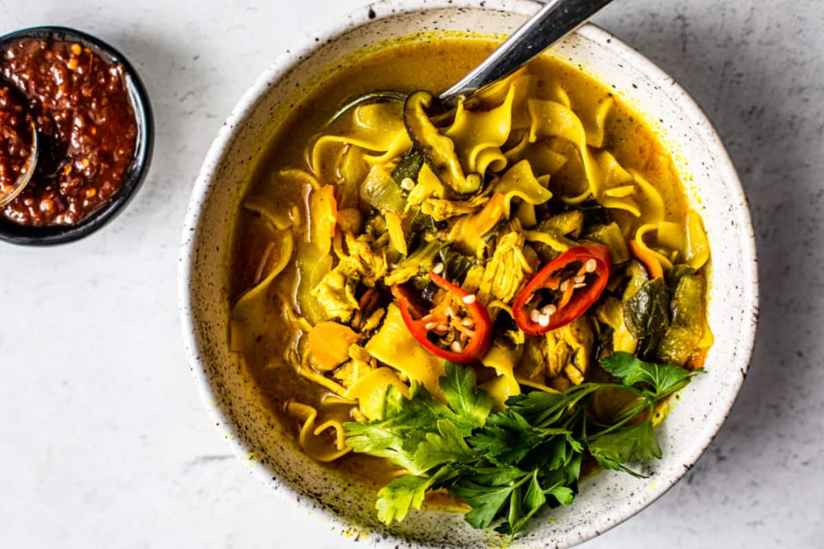 A bowl of spicy curry chicken noodle soup.