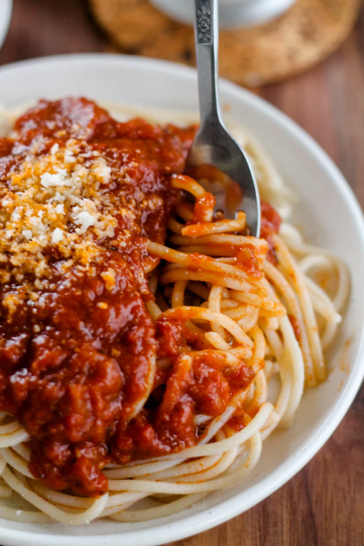 A fork twirling pasta with rich tomato sauce.