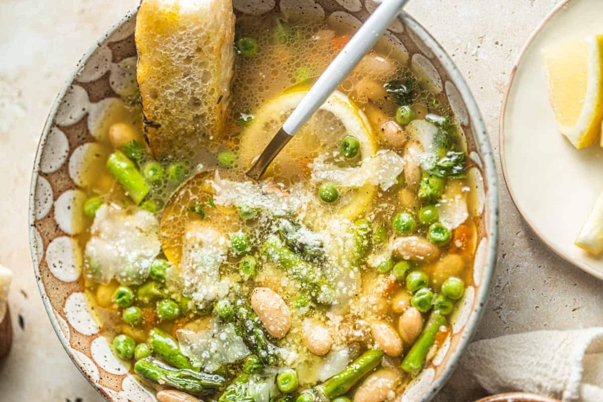 A bowl of One-Pot Lemon Bean Soup with Parmesan and Peas.