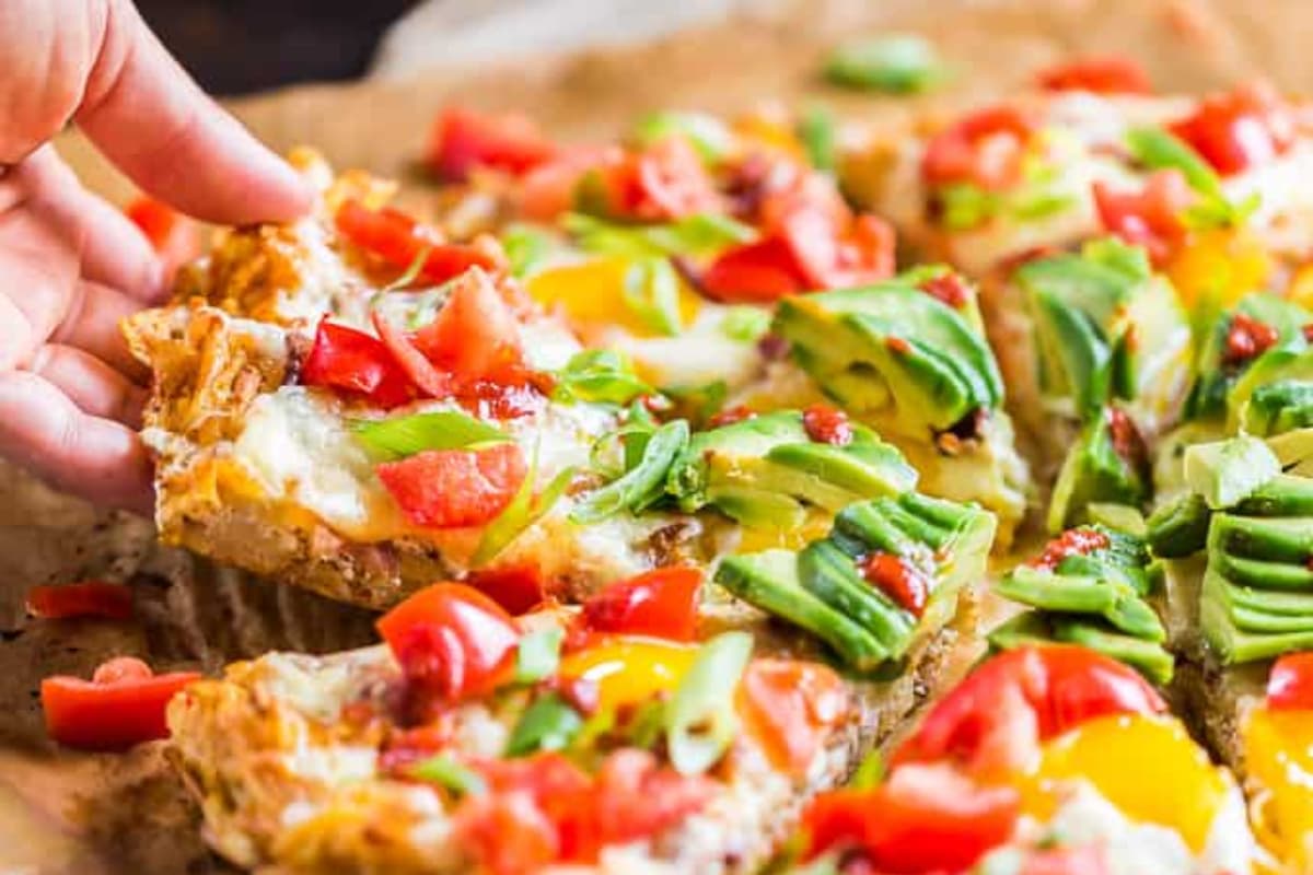 A plate of Bacon and Eggs Breakfast Pizza with Hashbrown Crust.