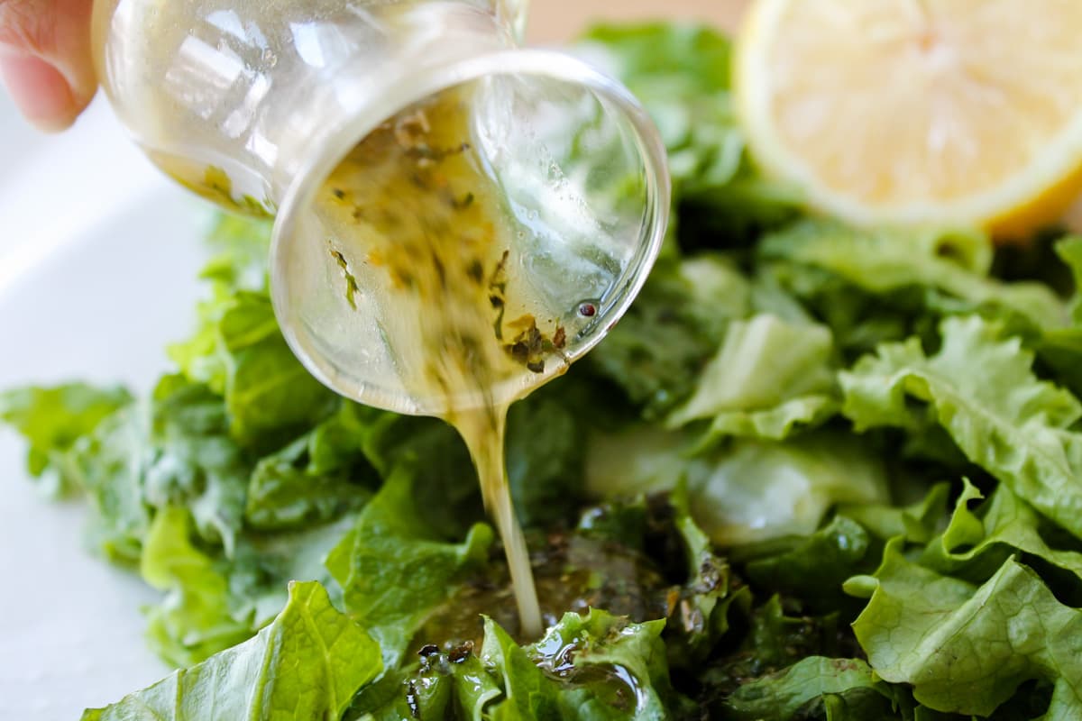 Homemade Italian dressing being poured onto salad.