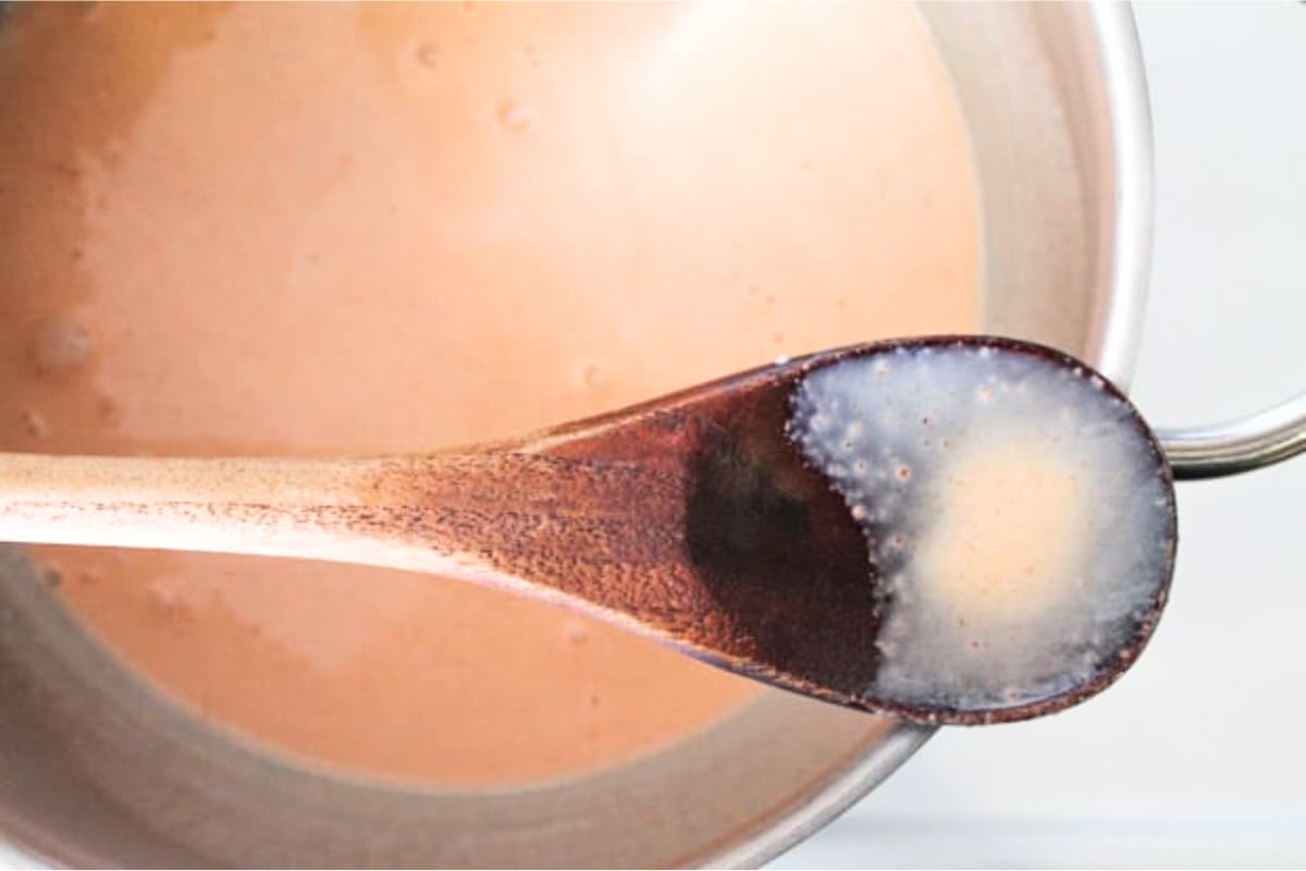 A spoon stirring ingredients in a soup pot.