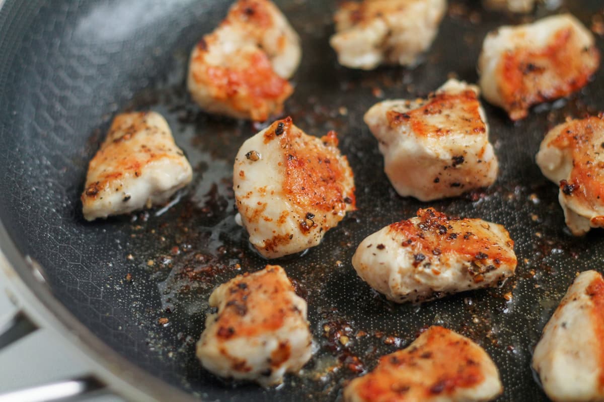 Chicken pieces in a pan.