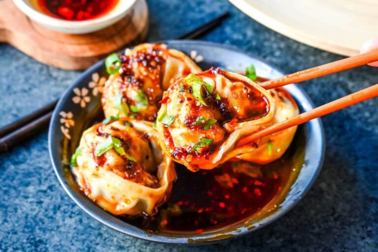 A plate of Spicy Wonton Dumplings with Chili Sauce.