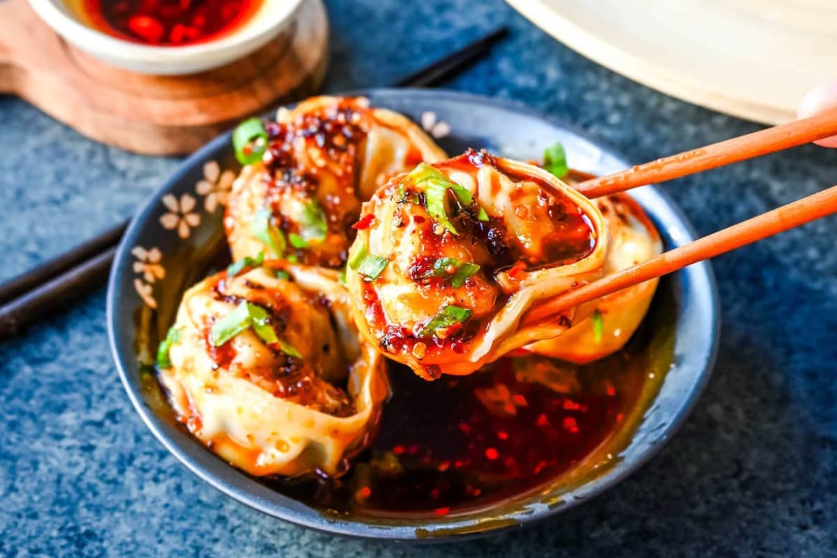 A plate of Spicy Wonton Dumplings with Chili Sauce.