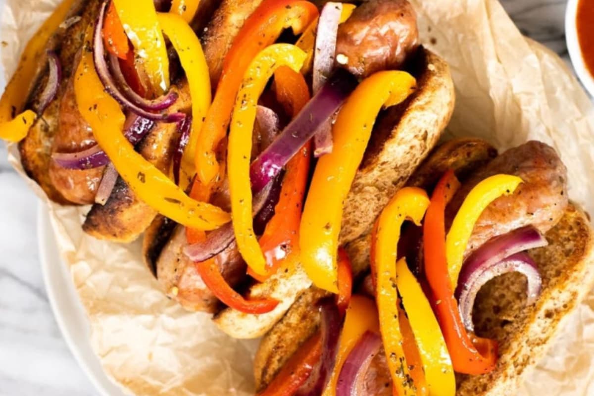 A plate of Sheet Pan Sausage and Peppers on a Bun.