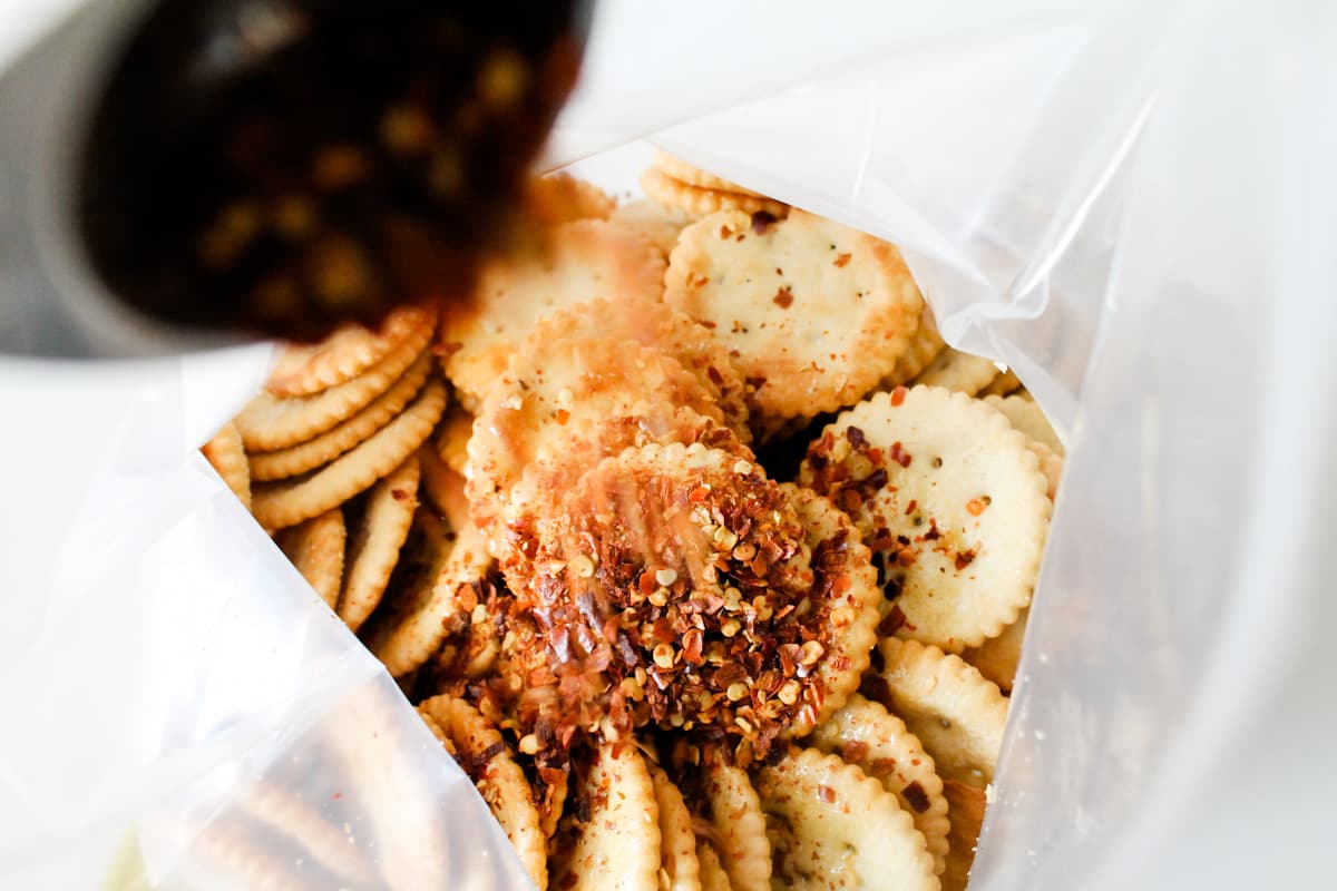 A bag of crackers with seasonings being sprinkled on top.