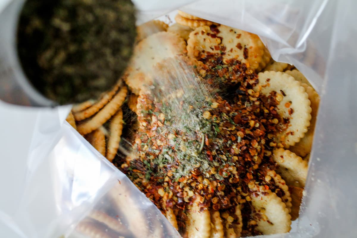 Spices being sprinkled onto a bag of crackers.
