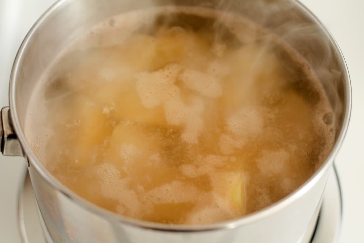 A pot of potatoes boiling on a stove.