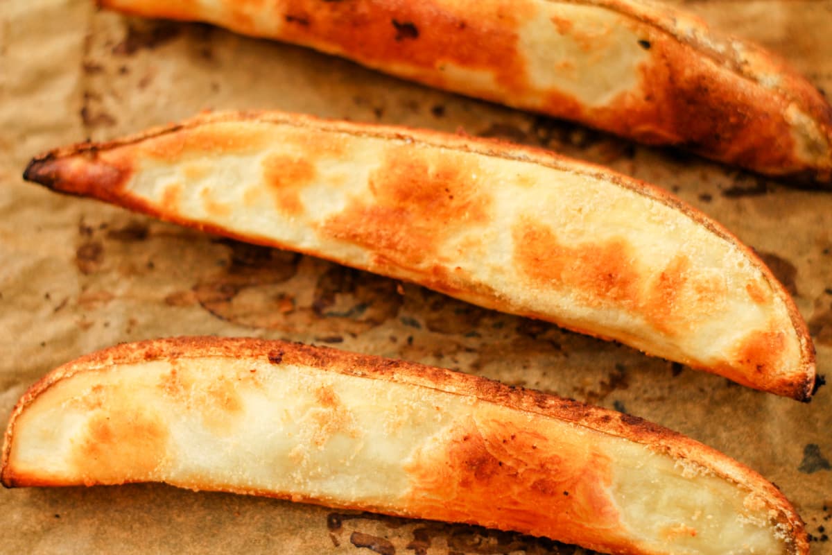 A tray of baked potato wedges coming out of the oven.