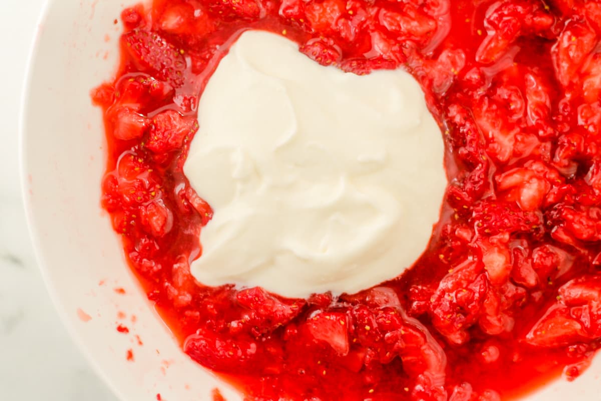 A bowl of strawberries with a dollop of yogurt.