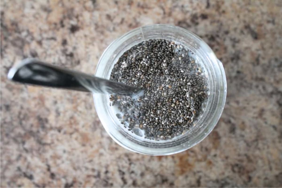 A jar of chia seeds being stirred into milk.