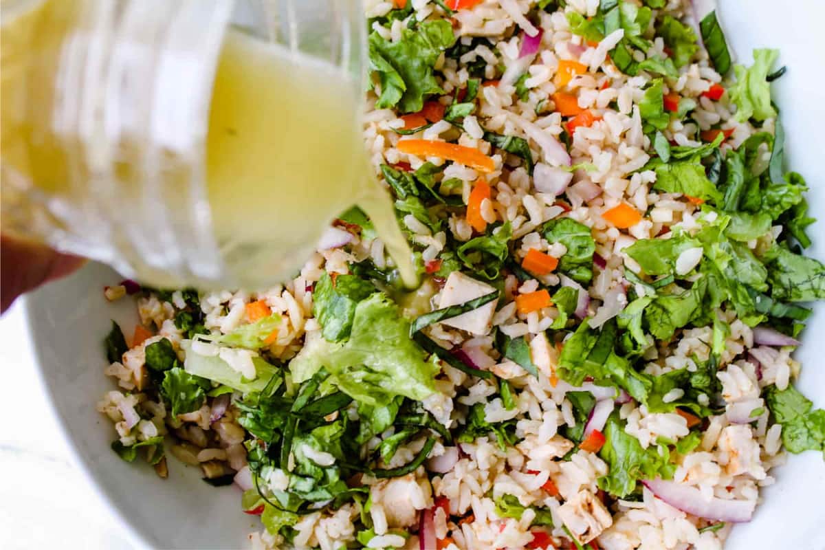 Dressing being poured over a rice salad.