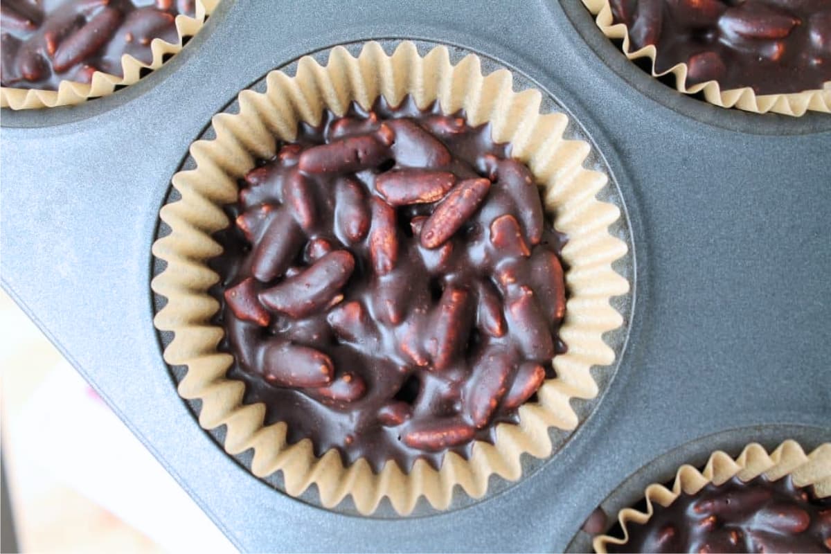 Chocolate mixture in a lined muffin tin.