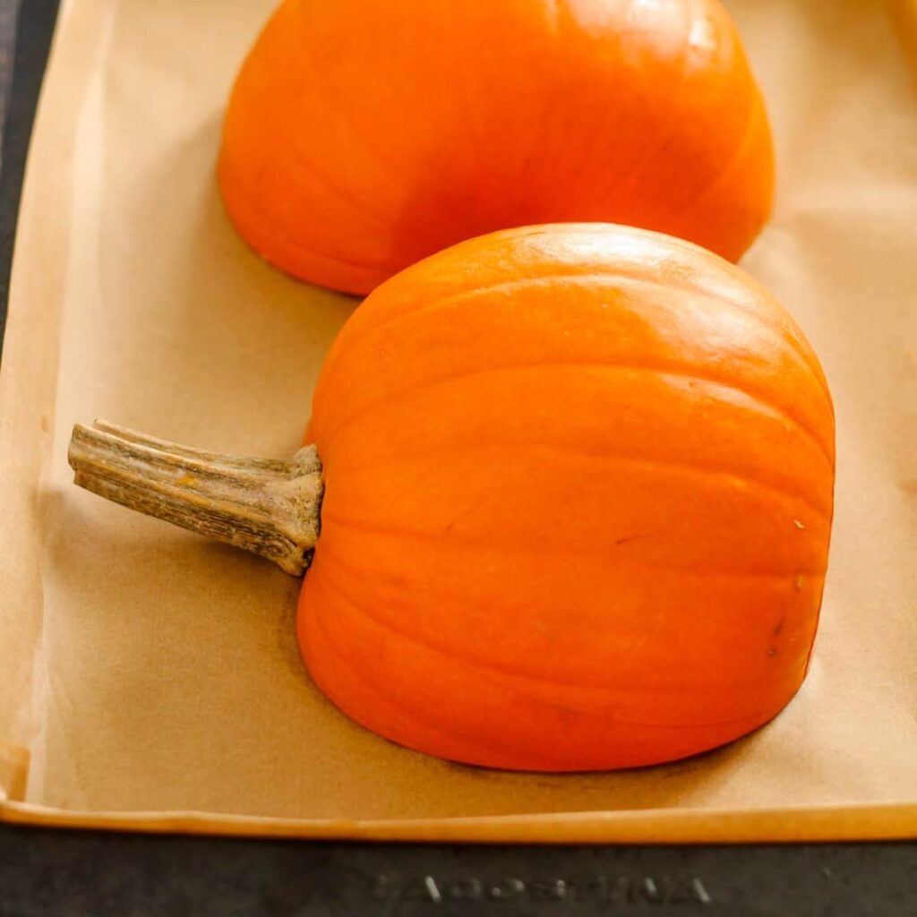 A baking sheet with pumpkins about to be roasted.