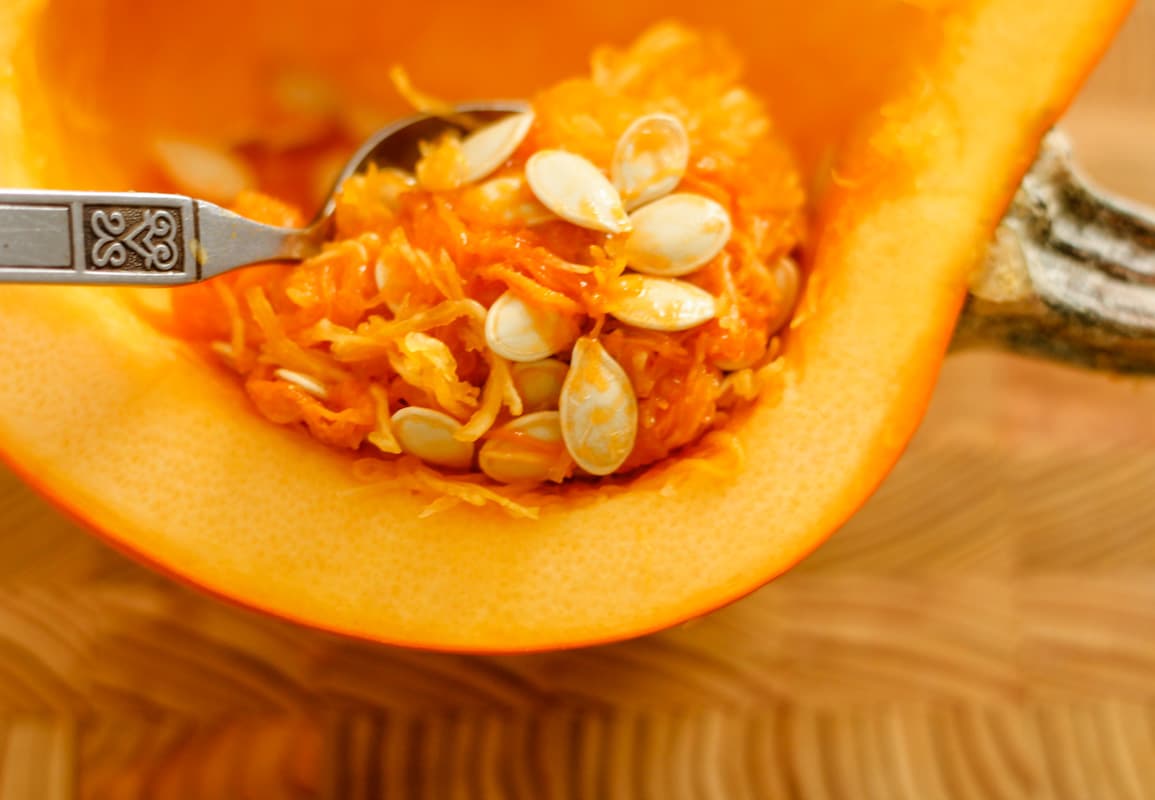 A spoon scooping the inside of a pumpkin.