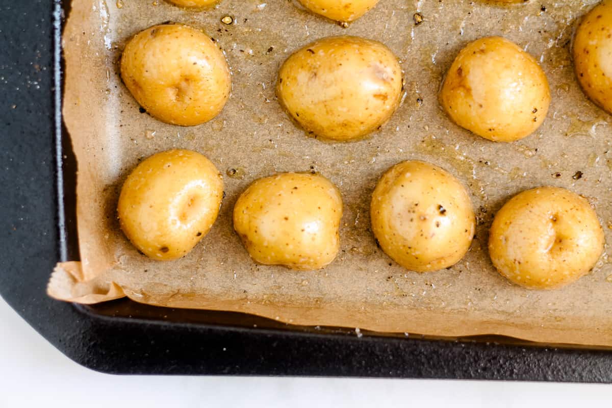 Potatoes on a sheet pan cut side down.