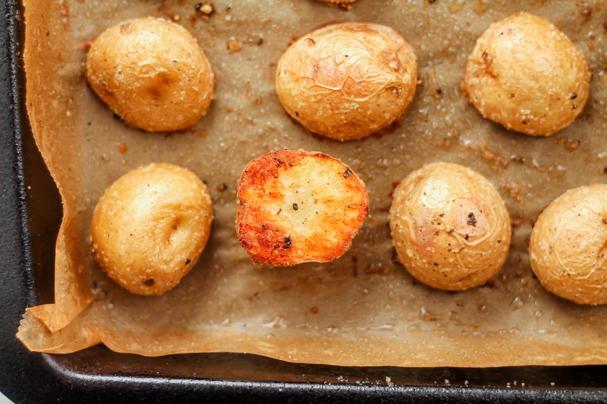 Potatoes flipped over on a sheet pan.