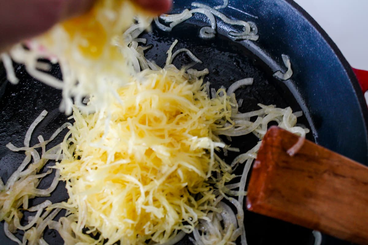 Spaghetti squash being added into a skillet.
