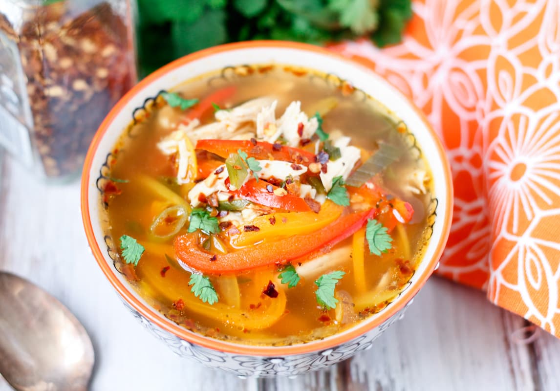 A bowl of chicken soup with peppers.