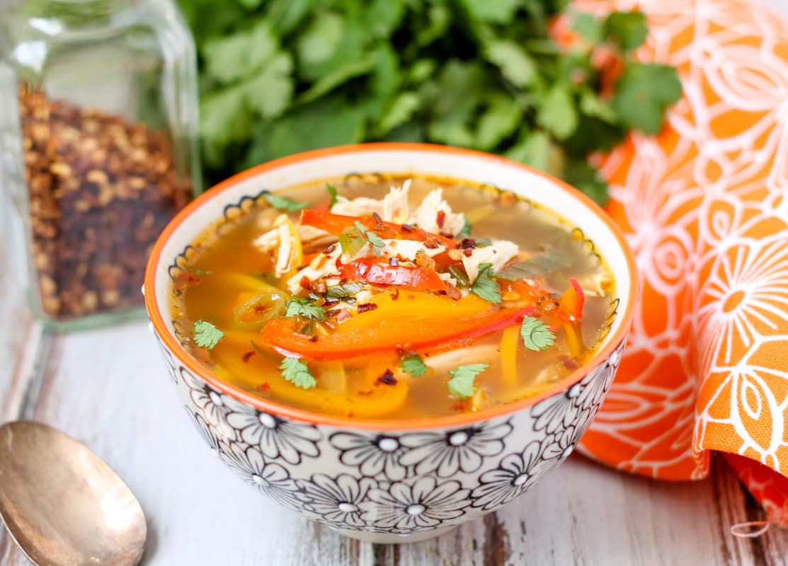 A bowl of chicken soup with peppers.