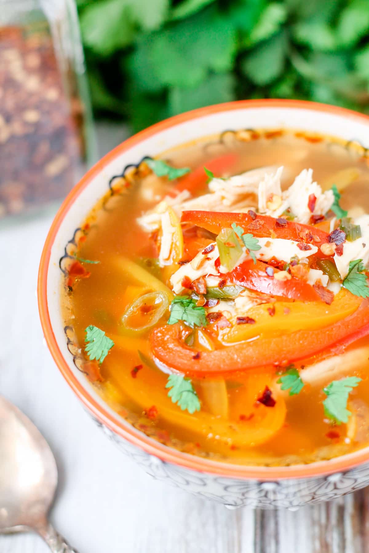A bowl of chicken soup with peppers.