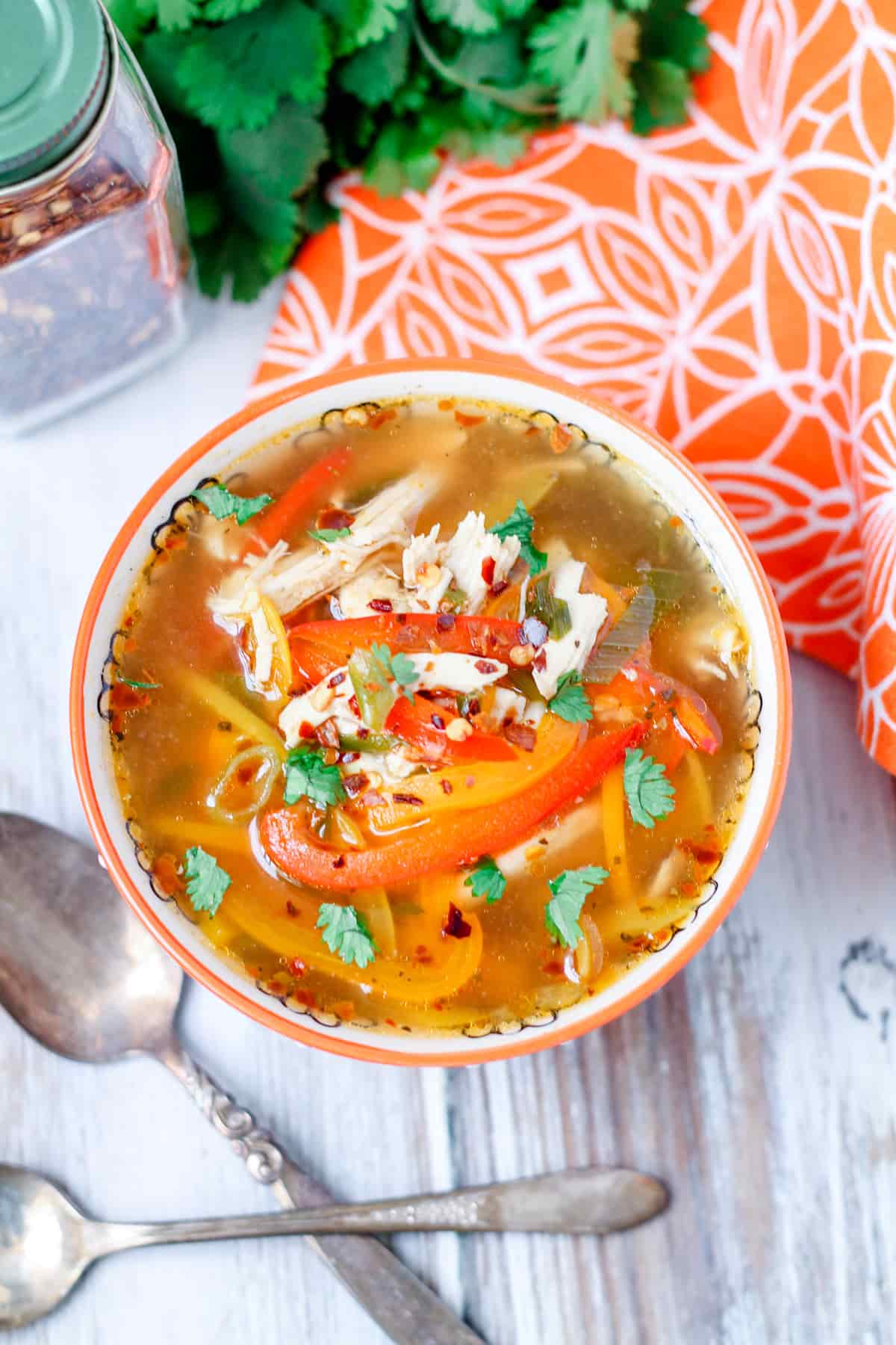 A bowl of chicken soup with peppers.