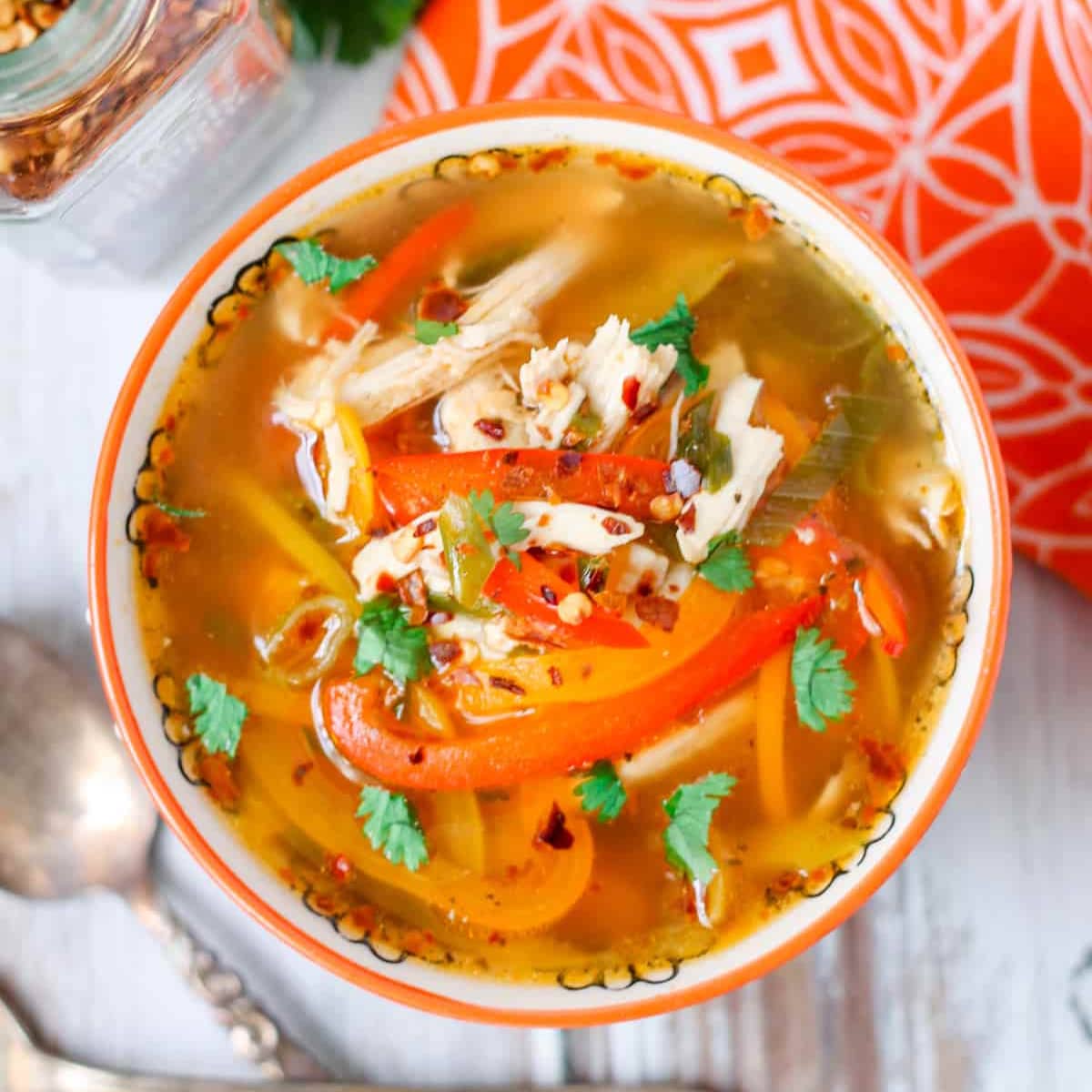 A bowl of chicken soup with peppers.